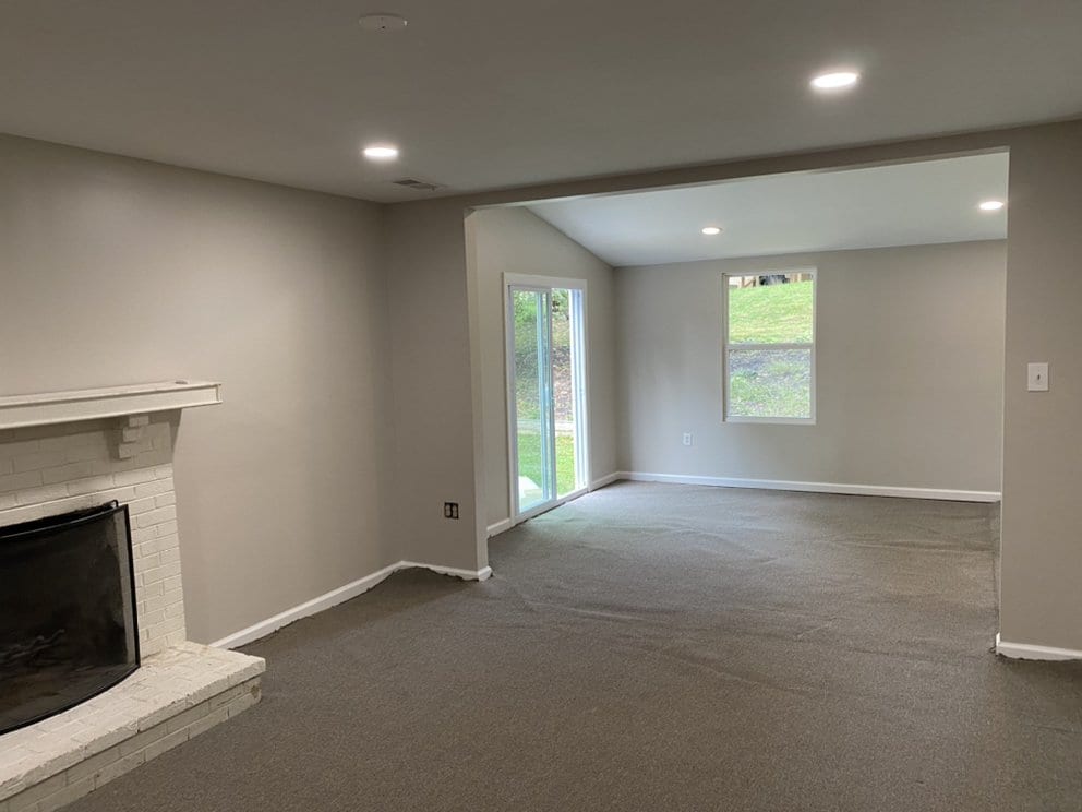 Finished basement rec room with painted walls, carpet, recessed lighting, a fireplace and a garden door.