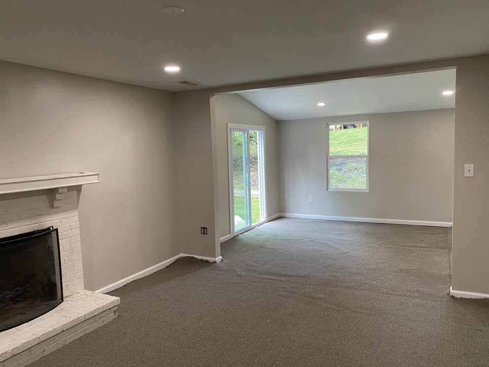 Finished basement rec room with painted walls, carpet, recessed lighting, a fireplace and a garden door.